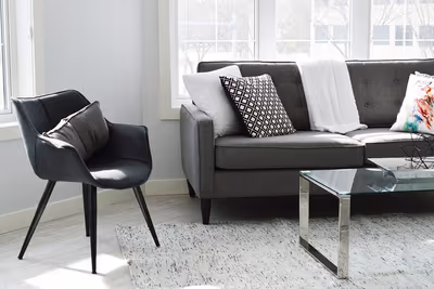 Wohnzimmer mit grauem Sofa, Sessel und Glastisch – ohne Sitzsack