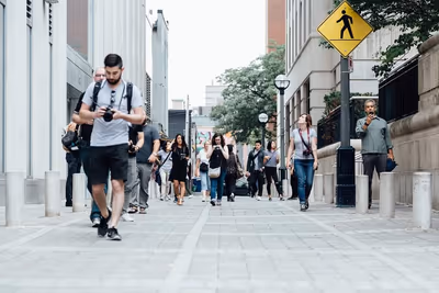 Fußgänger auf einem breiten Gehweg zwischen Bürogebäuden